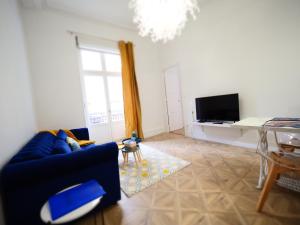 a living room with a blue couch and a tv at Les Ambassadeurs quartier Opéra in Vichy