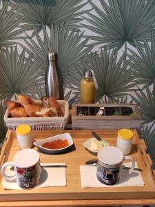 a wooden table with a tray of bread and coffee cups at De la mer Chambre d'hôtes in Colleville-Montgomery +7 photos