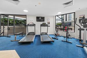CBD 1-Bed with Pool, Gym & City Views في بريزبين: صالة ألعاب رياضية مع أجهزة جري ومعدات للقلب في مبنى