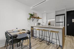 a kitchen with a counter and stools and a table at City High-Rise 1-Bed with Pool, Gym and Parking in Brisbane