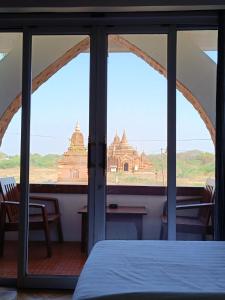 a room with a view of a building through a window at Temple View Hotel in Bagan