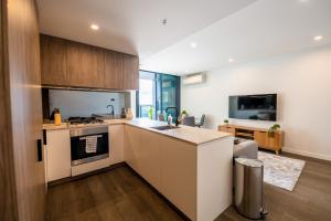 cocina con armarios blancos y fogones en Sleek 1-Bed Apartment With Rooftop Pool en Brisbane