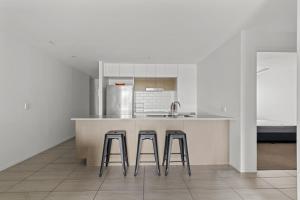 a kitchen with a counter and two bar stools at Sleek City Apartment with Parking and Balcony in Brisbane