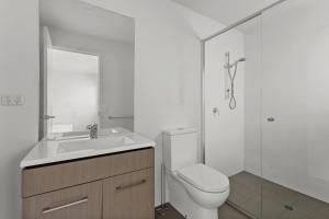 a bathroom with a toilet and a sink and a shower at Sleek City Apartment with Parking and Balcony in Brisbane