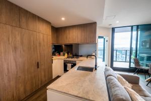 una cocina con armarios de madera y un sofá en una habitación en Sleek 1-Bed Apartment With Rooftop Pool en Brisbane
