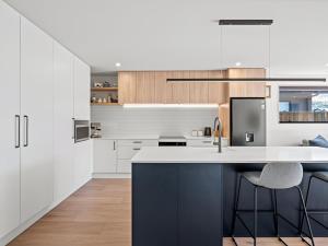 a kitchen with white cabinets and a blue island with stools at Remarkable stay in Queenstown in Frankton Wharf