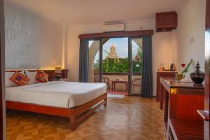 a bedroom with a bed and a balcony with a view at Temple View Hotel in Bagan