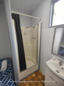 y baño con ducha y lavamanos. en Wagga Wagga Tourist Park, en Wagga Wagga