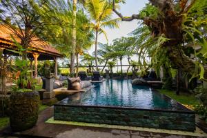 uma piscina no meio de um resort com palmeiras em Prabhu Ubud Villa em Ubud