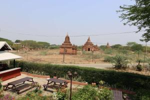 un groupe de bancs et de temples dans un champ dans l'établissement Myanmar Nan Hteik Temple View Hotel, à Bagan