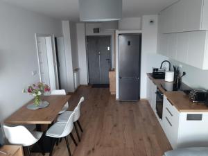 eine Küche mit einem Holztisch und weißen Stühlen in der Unterkunft Apartament Browarna in Nowy Sącz
