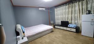 Dormitorio pequeño con cama y nevera en Green Valley en Sancheong