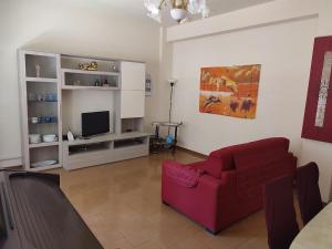 a living room with a red couch and a tv at Sun & Beach Vasco De Gama by ACS HOLIDAYS in Lido di Ostia