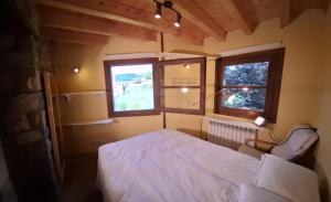 a bedroom with a white bed and two windows at Casa Guardafuentes de Ordesa ,Casa del Guardés in Buerba