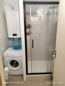 a glass shower in a bathroom with a washing machine at location appartement T1 hyper centre 350 m des thermes 200 m des télécabines deuxième étage avec ascenseur in Luchon