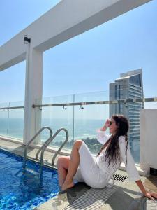 a woman in a white dress sitting next to a swimming pool at Tuyet Son Hotel (TS Ocean Hotel) in Da Nang