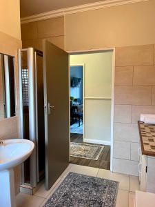 ein Bad mit einem Waschbecken und einer Tür, die in ein Zimmer führt in der Unterkunft Aan d'Oewer in Citrusdal