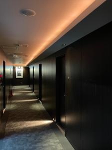 un couloir d'un bâtiment aux murs et aux portes noirs dans l'établissement Hotel BIX Tokyo Gotanda, à Tokyo