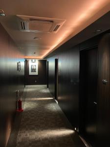 東京にあるHotel BIX Tokyo Gotandaの黒壁の長い廊下、ドアのある廊下