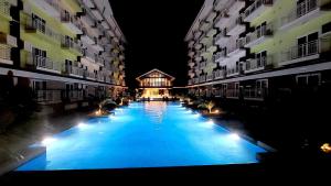 a large swimming pool between two buildings at night at ANIA ROOMS@AMANI GRAND RESIDENCES NEAR AIRPORT in Mactan