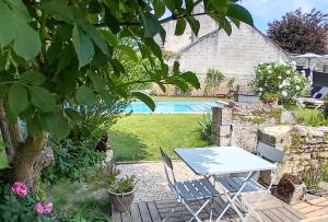 uma mesa e cadeiras num jardim com piscina em Le Clos de l'Aiguillon 