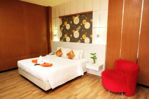 um quarto com uma cama e uma cadeira vermelha em Halogen Hotel Airport Surabaya em Sidoarjo