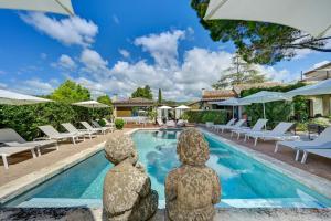 a villa with a pool with two statues in front of it at Hotel Bastide & SPA - Villa de Lourmarin in Lourmarin +138 photos