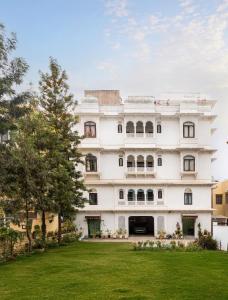 a white building with a green lawn in front of it at Chandra Vilas Heritage stay in Udaipur