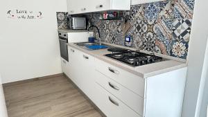 uma cozinha com armários brancos e um fogão em casa Mari, 250 mt dalle spiagge em Diano Marina
