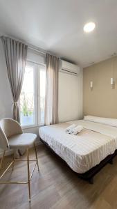 a bedroom with a bed and a chair and a window at Hermosos Apartamentos en pleno Centro in Granada