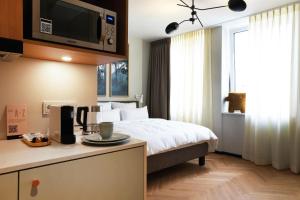 une chambre d'hôtel avec un lit et une télévision murale dans l'établissement Hood House Kassel, à Cassel