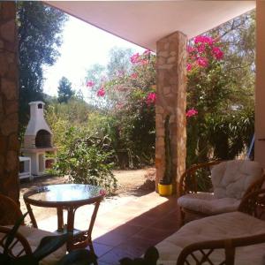 a patio with a table and chairs and flowers at Villa dei Pini , Solanas Villasimius in Solanas