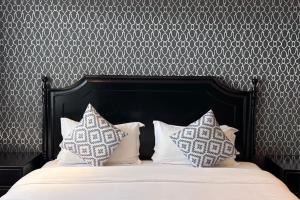 - un lit avec une tête de lit noire et 2 oreillers dans l'établissement Glory Boutique Suites 清迈古城荣耀精品酒店, à Chiang Mai
