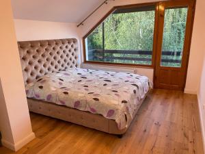 a bed in a bedroom with a large window at VILLA BY THE LAKE in Curtea de Argeş