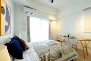 a bedroom with a bed and a table and a window at ZOOM江坂公園 - For long stay, Shin Osaka in Osaka