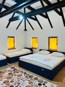 two beds in a room with yellow windows and a rug at Small Bosnian House in Bihać +35 photos