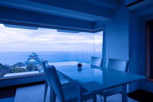 a dining room with a table and a large window at Mujuan in Atami