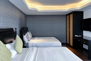 une chambre d'hôtel avec deux lits et une télévision dans l'établissement Glory Boutique Suites 清迈古城荣耀精品酒店, à Chiang Mai