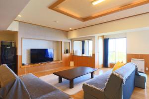 a living room with a couch and a table at 熱海 天空のホテル 夢寿庵-Mujuan- in Atami