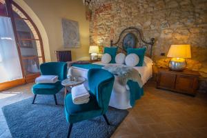 1 dormitorio con cama, sillas y pared de piedra en LaChiusa Tuscany, en Montefollonico