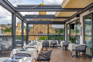 een restaurant met tafels en stoelen en uitzicht op een gebouw bij Iris Hotel in Tbilisi City