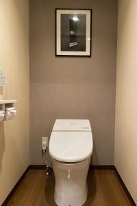 - des toilettes blanches dans une salle de bains avec une photo sur le mur dans l'établissement Hotel BIX Tokyo Gotanda, à Tokyo