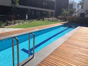 a swimming pool with a wooden walkway next to a building at Air Conditioned One Bedroom with Pool Close To CBD in Sydney