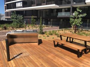 a grill and a bench on a wooden deck with a building at Air Conditioned One Bedroom with Pool Close To CBD in Sydney