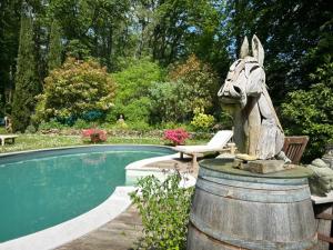 a statue of a horse standing next to a pool at GITES du BOIS des PERRUCHES in Saint-Vincent-des-Bois