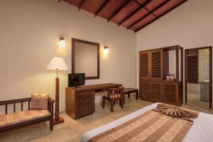 1 dormitorio con cama, escritorio y espejo en River Loft Nature Resort, en Pathegama