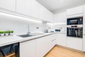 a white kitchen with white cabinets and a sink at Pluxa Moonstone Metropolis Luxury Getaway in Birmingham City Centre in Birmingham +12 photos