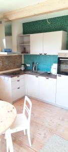 a kitchen with white cabinets and a table and a table and chair at ländlicher öko-flair im Strohhaus in Frickingen +11 photos