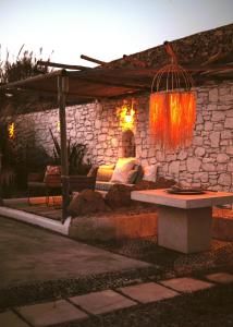 a patio with a couch and a table in front of a stone wall at Sea Side Studios & Houses in Kalo Livadi