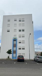 a white building with a car parked in a parking lot at Ranjeet felizarda in Lisbon